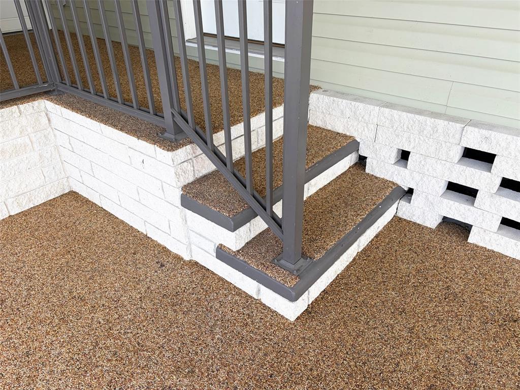 An exterior view of a porch with stone-textured steps, a metal railing, and white blocks — 1503 23RD AVENUE W, BRADENTON, FL