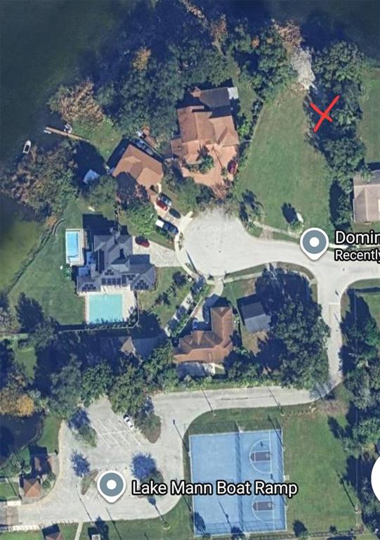 This aerial view shows a residential neighborhood with houses, a basketball court, and a lake — DOMINO COURT LOT 9, ORLANDO, FL