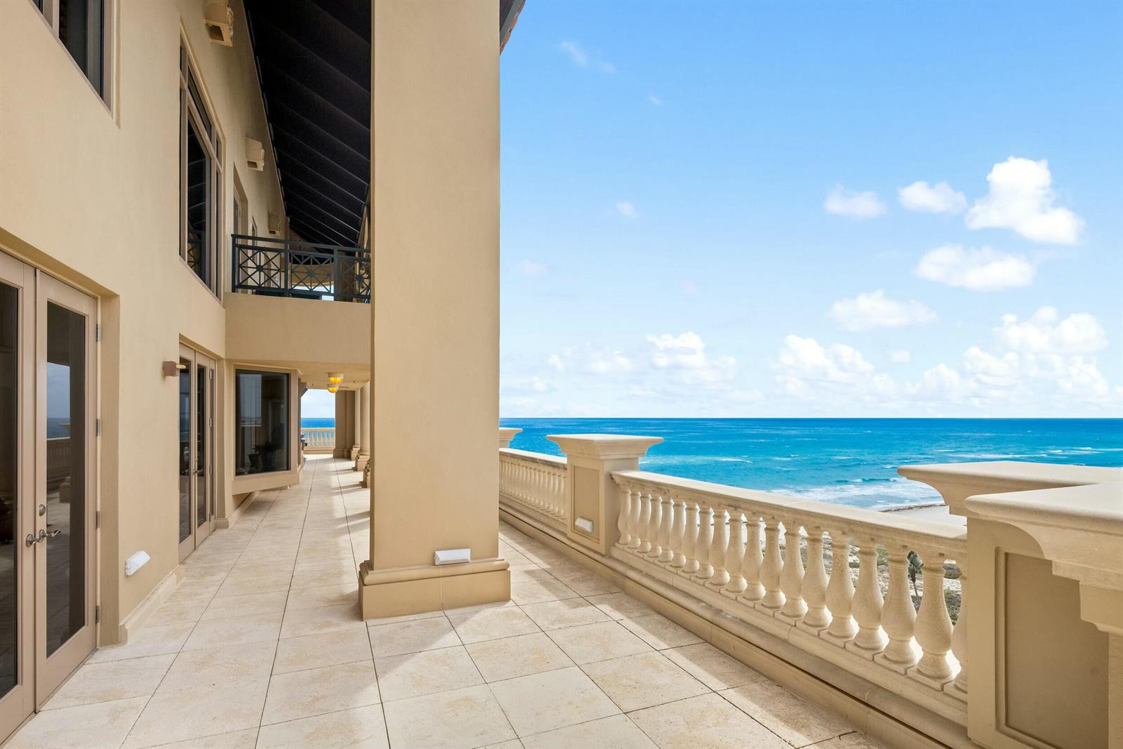 A spacious stone-tiled balcony with a balustrade railing overlooks the blue ocean — 2500 S Ocean Boulevard # 903, Boca Raton FL 33432, BOCA RATON, FL