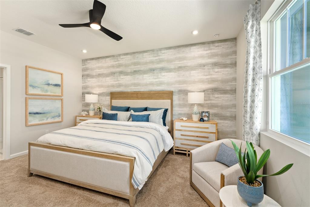 A bedroom features a wood-paneled accent wall, a bed with blue accents, and a chair — 156 RAINWOOD STREET, GROVELAND, FL