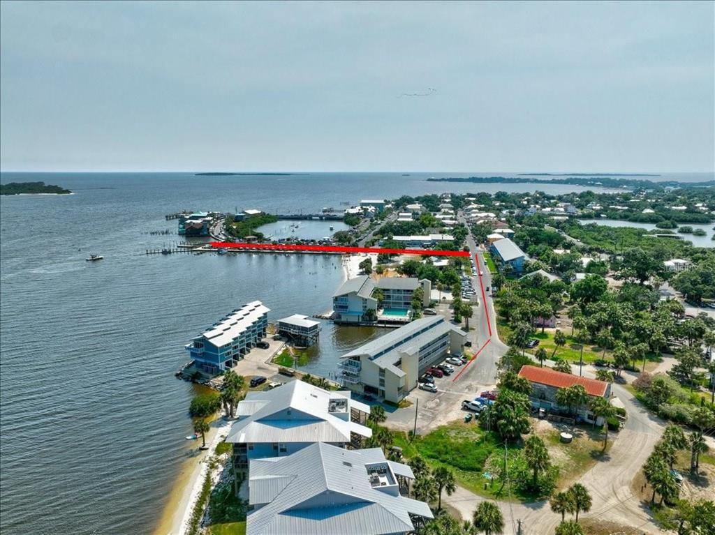 An aerial view shows a coastal town with a red line highlighting a waterfront pier — 82 2ND STREET UNIT D5, CEDAR KEY, FL