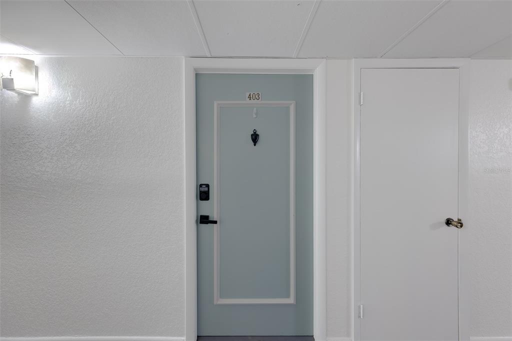 A light blue front door labeled 403 sits next to a plain white door — 19029 US HIGHWAY 19 N UNIT 9-403, CLEARWATER, FL
