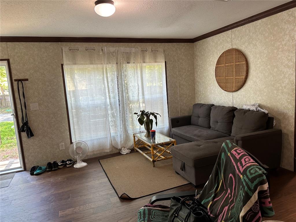 A living room features wood-look flooring, a gray sectional sofa, and a bamboo coffee table — 6735 SW 51ST AVENUE, GAINESVILLE, FL