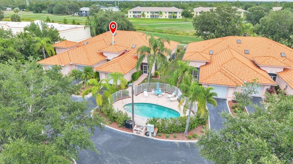 An aerial view of two pink villas with orange tile roofs and a shared pool — 1260 RIO DE JANEIRO AVENUE UNIT 102, PUNTA GORDA, FL