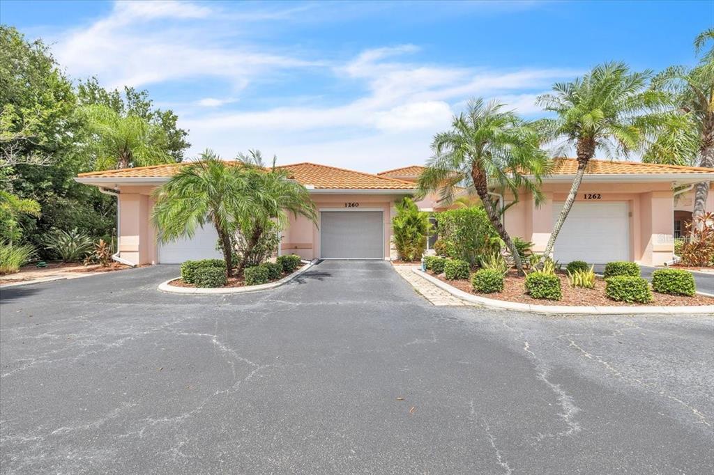 A multi-unit residential building with a paved driveway, palm trees, and three garage doors — 1260 RIO DE JANEIRO AVENUE UNIT 102, PUNTA GORDA, FL