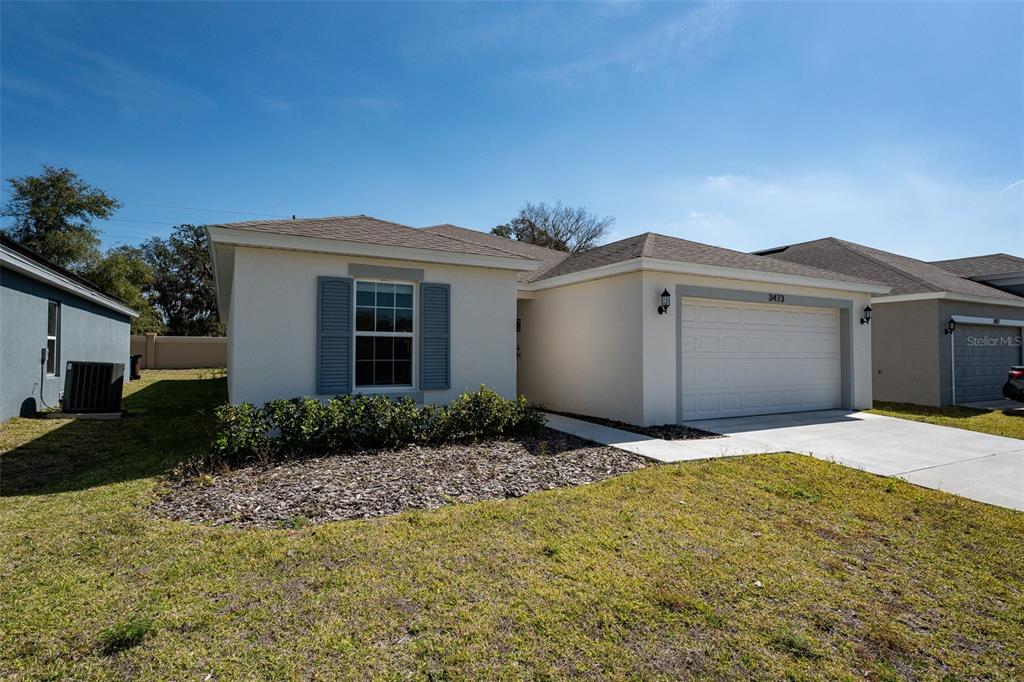 The exterior of a single-story house features a two-car garage and a front yard — 3473 YARIAN DRIVE, HAINES CITY, FL