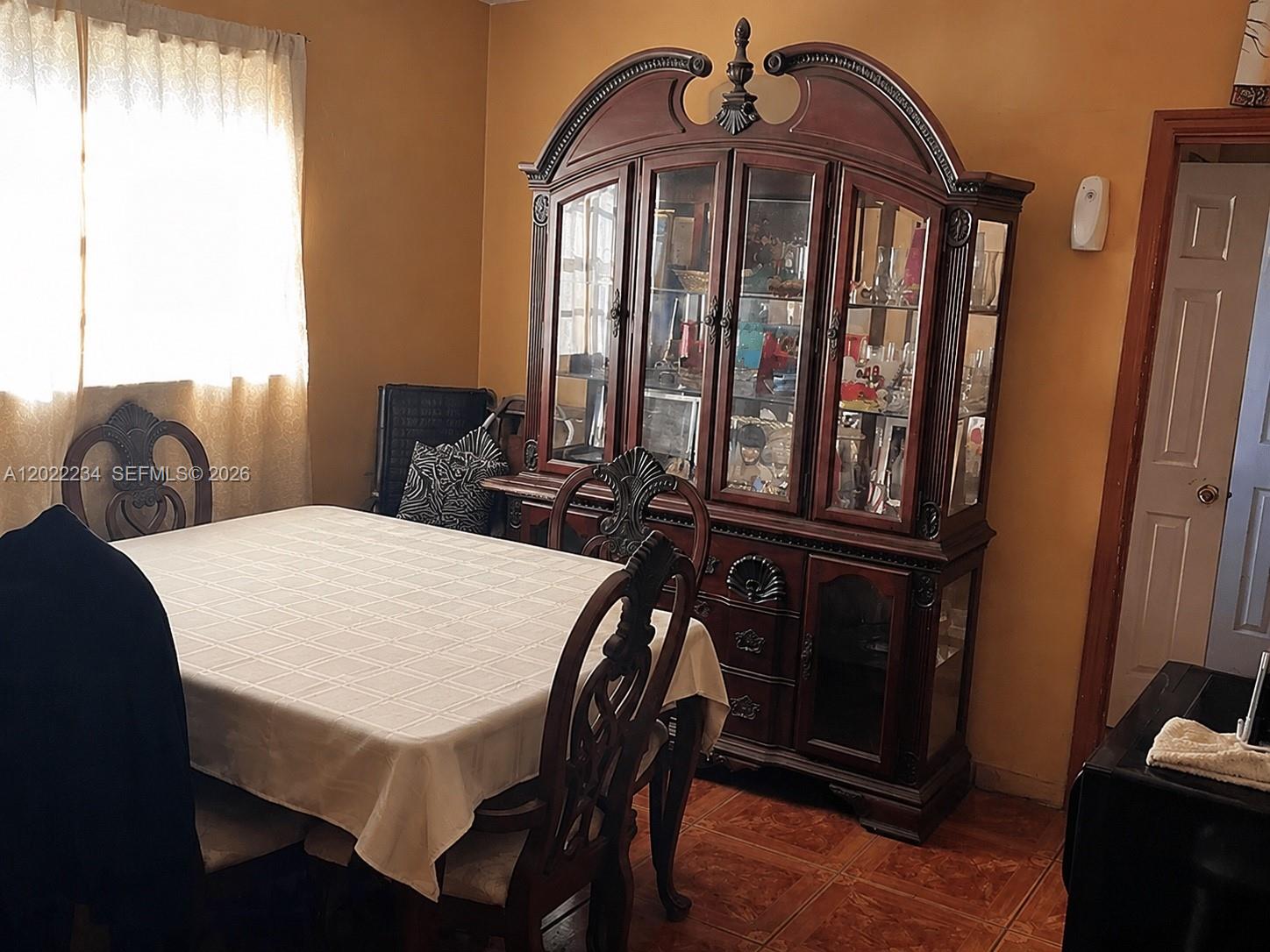A dining room features a wooden hutch, a table with a tablecloth, and chairs — 716 NW 4th St, Hallandale Beach FL 33009, HALLANDALE BEACH, FL