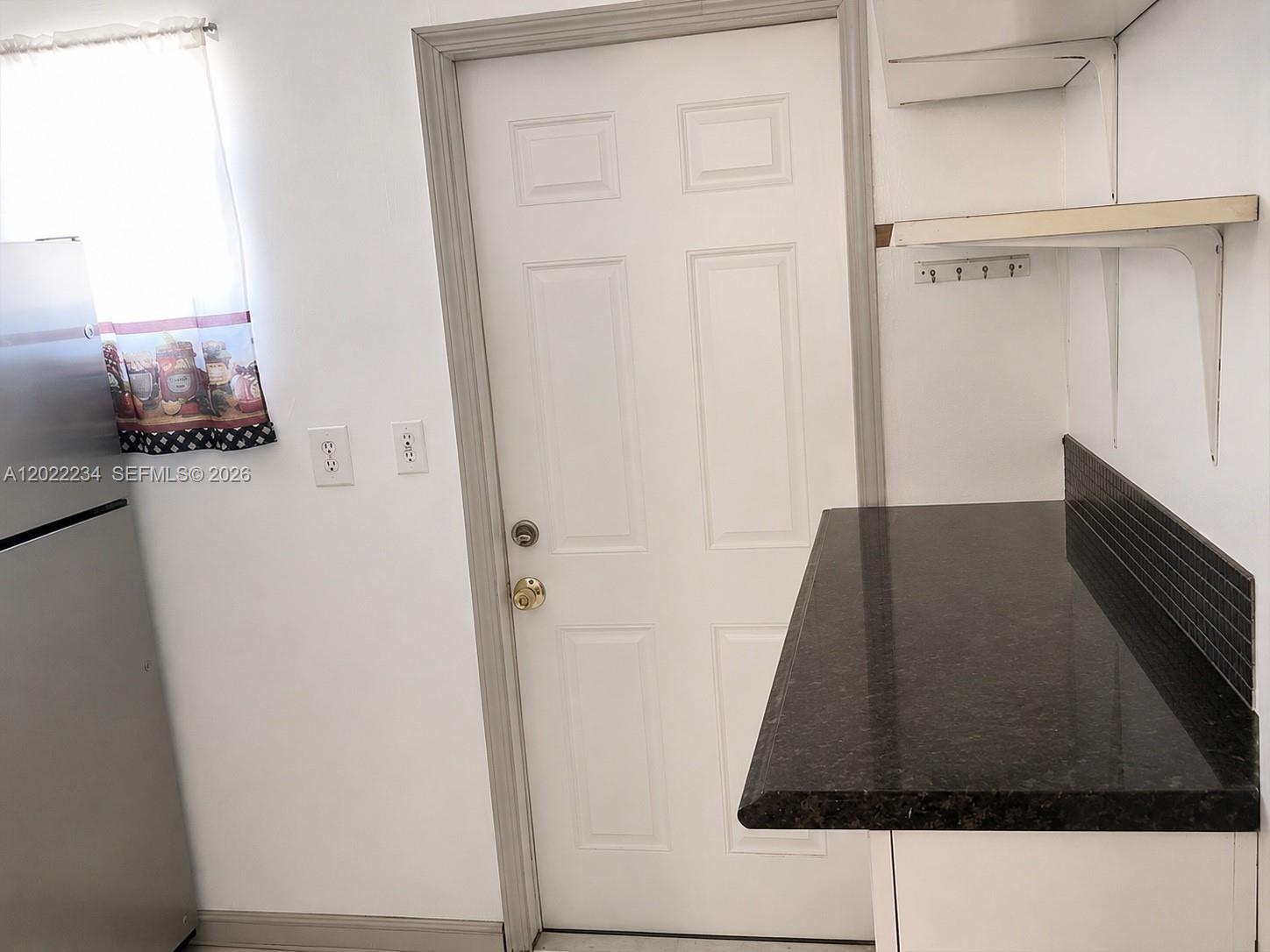 A kitchen features a stainless steel refrigerator, a white door, and a dark countertop — 716 NW 4th St, Hallandale Beach FL 33009, HALLANDALE BEACH, FL