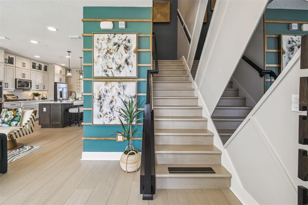 A staircase with light wood treads sits beside a teal accent wall with horizontal trim — 17106 BEACHGRASS ALLEY, WINTER GARDEN, FL
