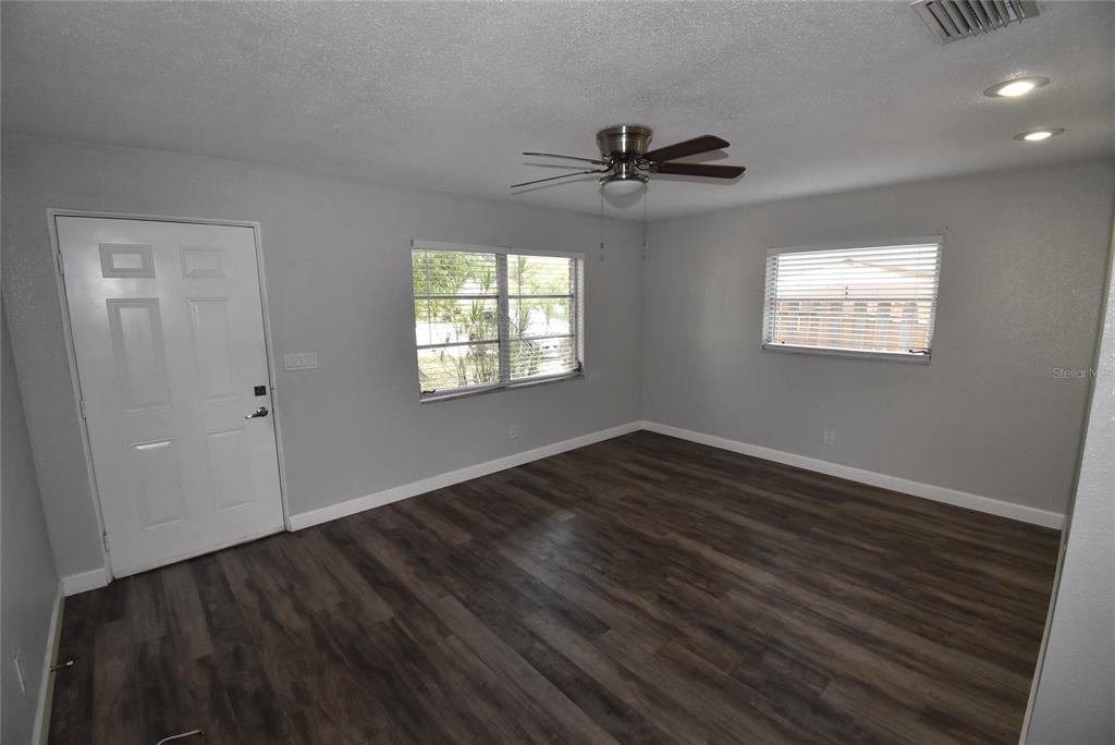 A room with gray walls, dark wood-look flooring, a ceiling fan, and two windows — 2713 26TH AVENUE N, ST PETERSBURG, FL