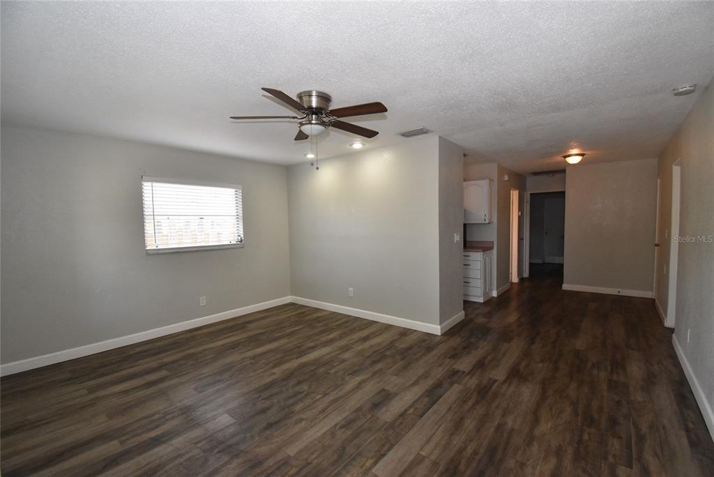 A living room with gray walls, wood-look flooring, a ceiling fan, and an adjacent kitchen — 2713 26TH AVENUE N, ST PETERSBURG, FL