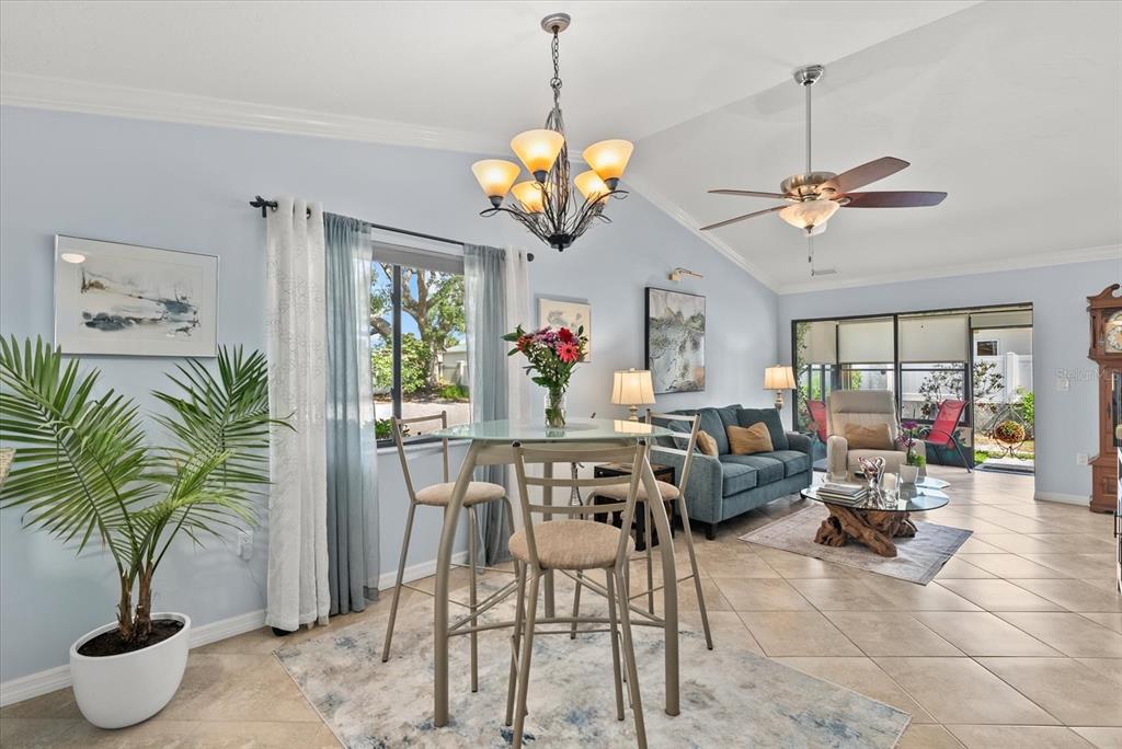 A dining area with a glass table and chandelier opens into a living room with tile — 2723 60TH AVENUE DRIVE W UNIT 2723, BRADENTON, FL