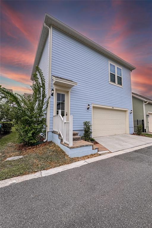 A two-story light blue house features a front-facing garage and a small elevated entryway — 13825 LIPPMAN ALY, ORLANDO, FL