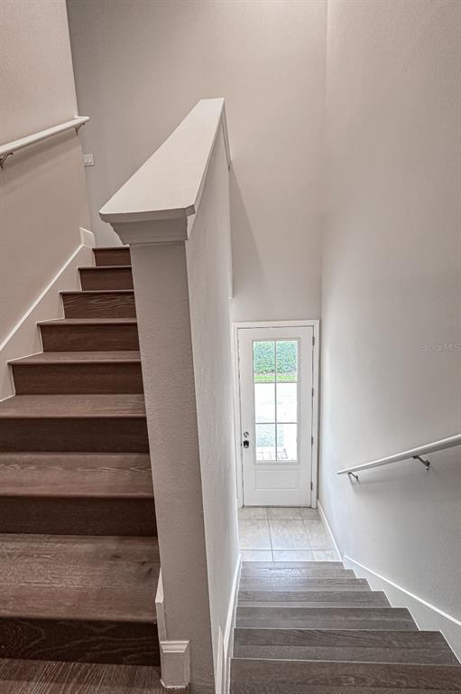 A staircase with dark wood treads leads to a landing with a white entry door — 13825 LIPPMAN ALY, ORLANDO, FL