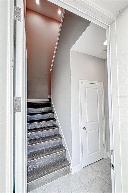A staircase with dark wood-look treads leads upward next to a white interior door — 13825 LIPPMAN ALY, ORLANDO, FL