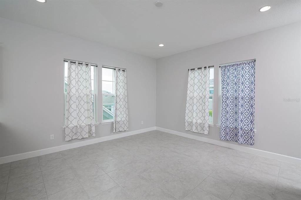 An empty room with light gray walls, tile flooring, recessed lighting, and four windows with curtains — 13825 LIPPMAN ALY, ORLANDO, FL