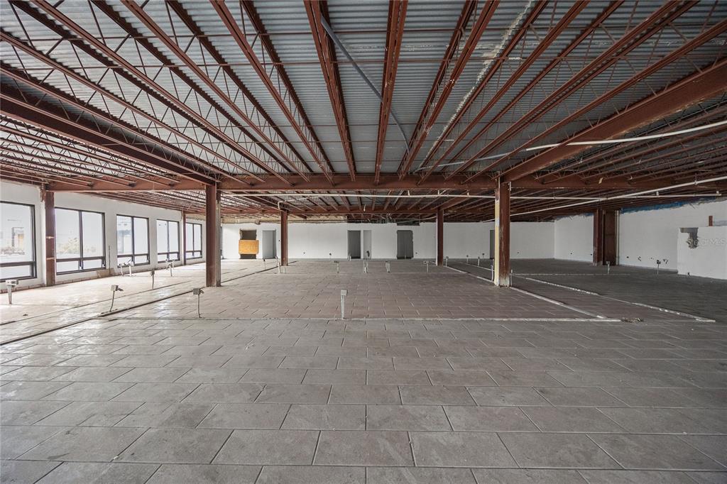 An expansive, unfinished commercial interior features exposed steel ceiling trusses and gray tiled flooring — 48 ESQUINA CORCHADO Y RUIZ BELVIS, CAGUAS, PR