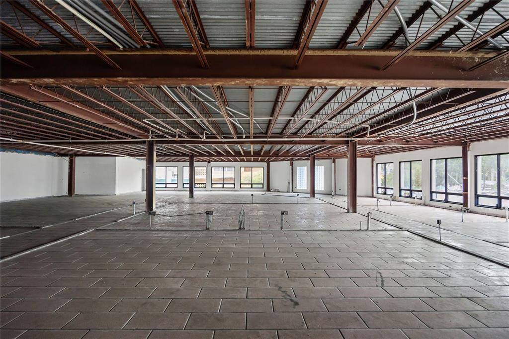 An open-plan commercial space features exposed steel ceiling beams, tiled flooring, and large windows — 48 ESQUINA CORCHADO Y RUIZ BELVIS, CAGUAS, PR