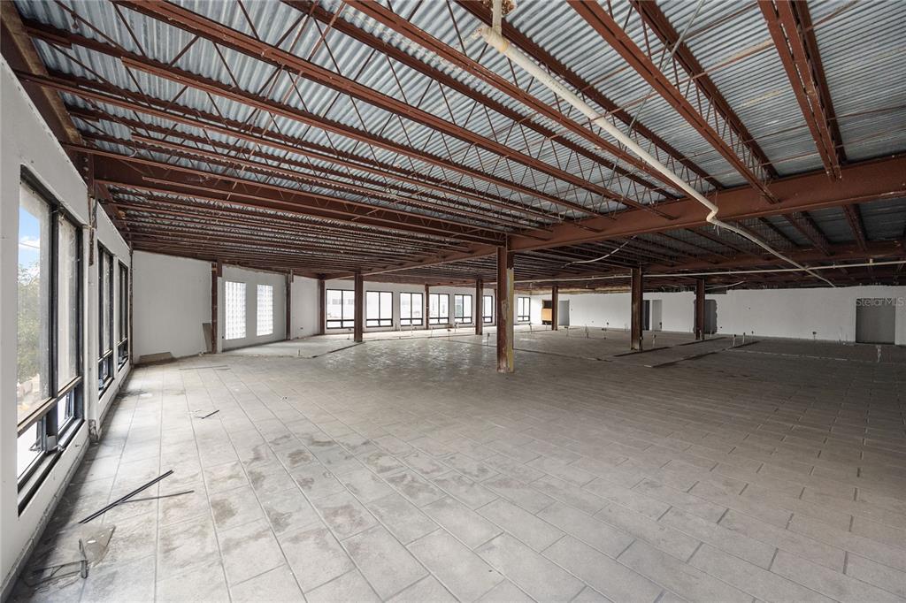 An open-plan commercial space with tiled floors, exposed ceiling beams, and large windows — 48 ESQUINA CORCHADO Y RUIZ BELVIS, CAGUAS, PR