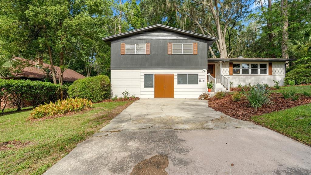 A two-story house with a white and dark gray exterior features a concrete driveway — 1114 NW 36TH DRIVE, GAINESVILLE, FL