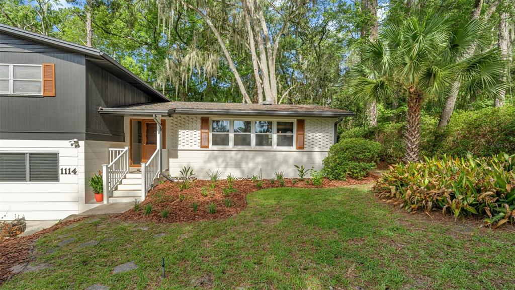 A split-level house with white brick, dark siding, and a front yard with a palm tree — 1114 NW 36TH DRIVE, GAINESVILLE, FL