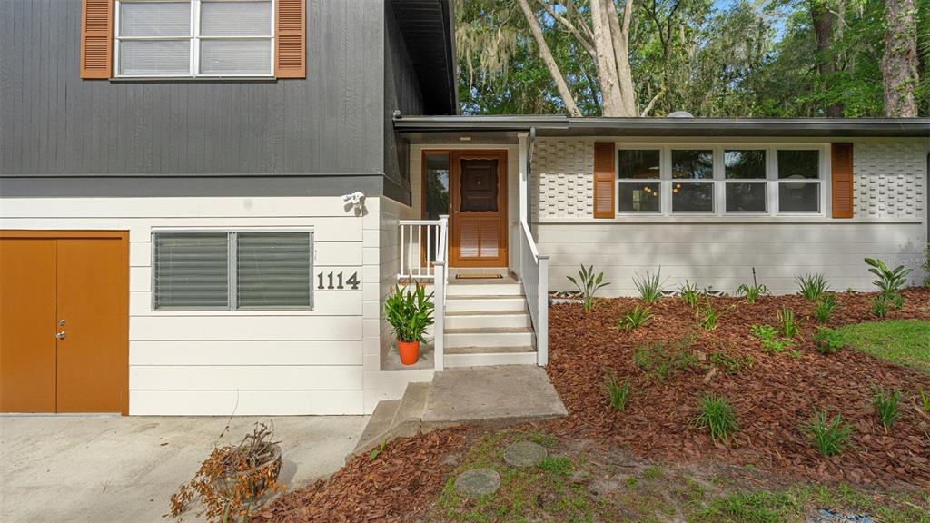 A two-story house exterior features a white lower level, dark gray upper level, and brown shutters — 1114 NW 36TH DRIVE, GAINESVILLE, FL
