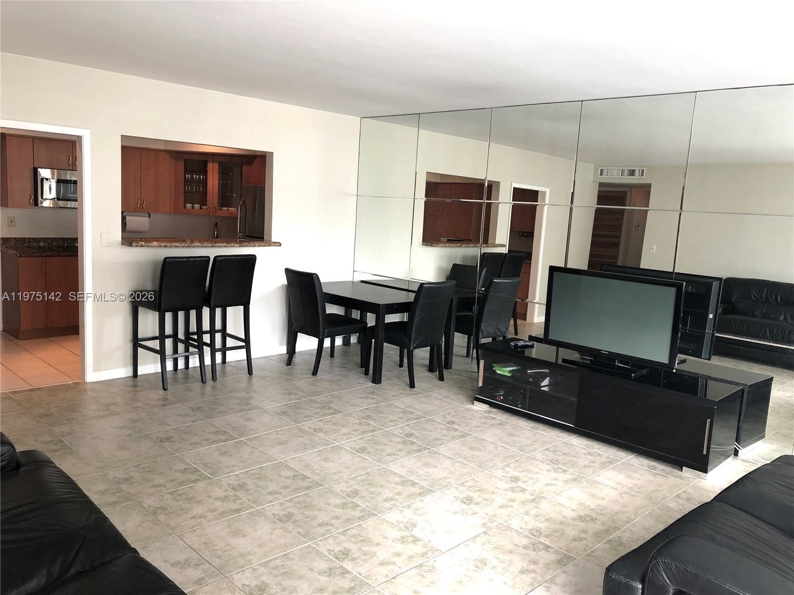 A living and dining area features tiled floors, a mirrored wall, and a kitchen pass-through — 1408 Brickell Bay Dr # 404, Miami FL 33131, MIAMI, FL