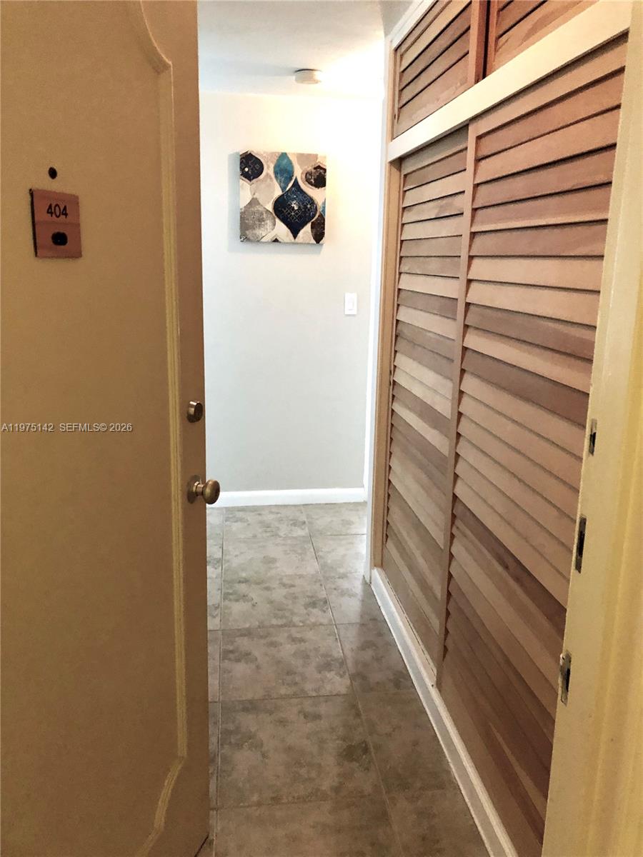 An entryway features tiled flooring, a louvered closet, and a wall-mounted abstract painting — 1408 Brickell Bay Dr # 404, Miami FL 33131, MIAMI, FL