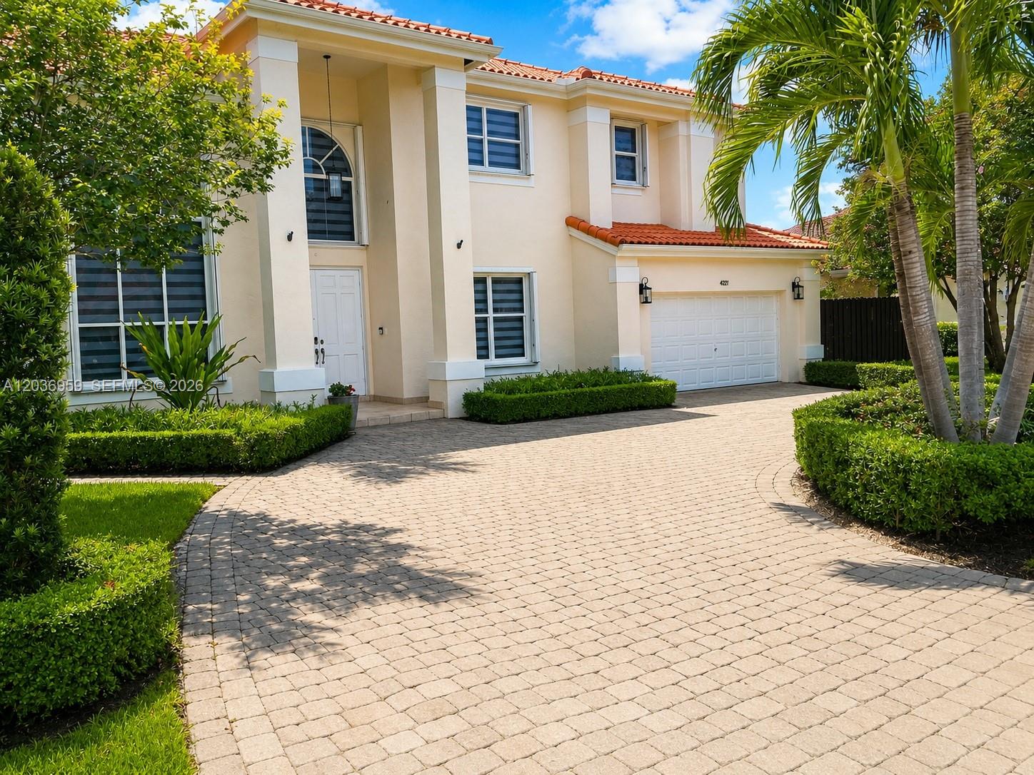 A two-story beige house features a tiled roof, arched window, and a paved circular driveway — 4221 SW 154th Pl, Miami FL 33185, MIAMI, FL