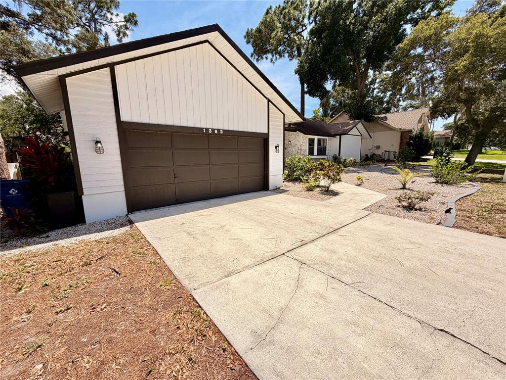 A white house with a brown garage door and a concrete driveway under a blue sky — 1382 SUTTON PLACE DRIVE, PALM HARBOR, FL