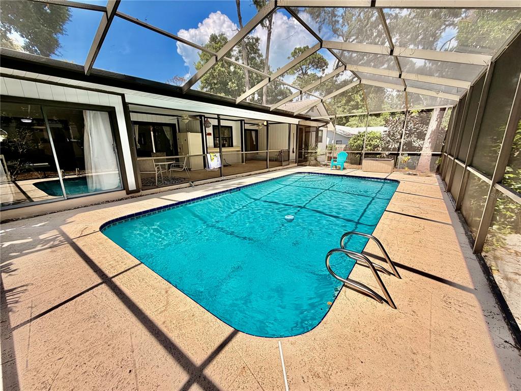A rectangular swimming pool sits inside a screened-in patio area with a concrete deck — 1382 SUTTON PLACE DRIVE, PALM HARBOR, FL