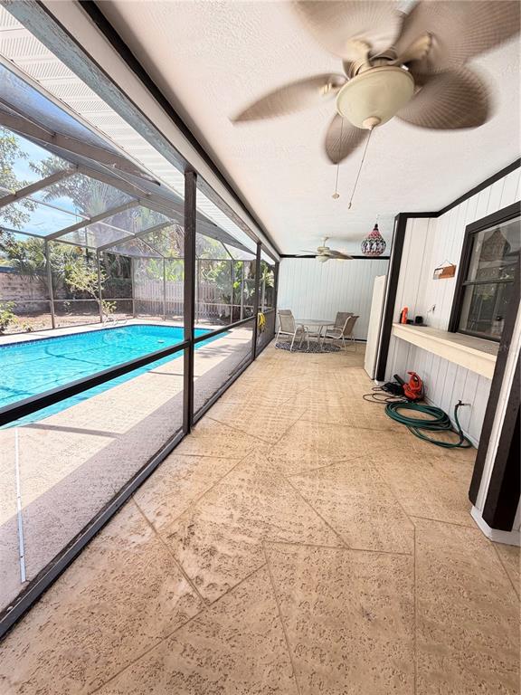 A covered patio with a textured concrete floor overlooks a screened-in swimming pool — 1382 SUTTON PLACE DRIVE, PALM HARBOR, FL