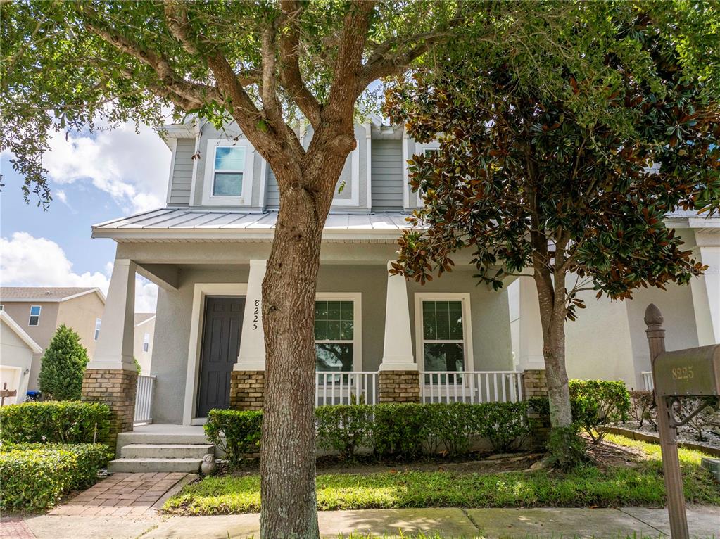 A two-story house with a front porch, gray siding, and a brick-accented foundation — 8225 BRYCE CANYON AVENUE, WINDERMERE, FL