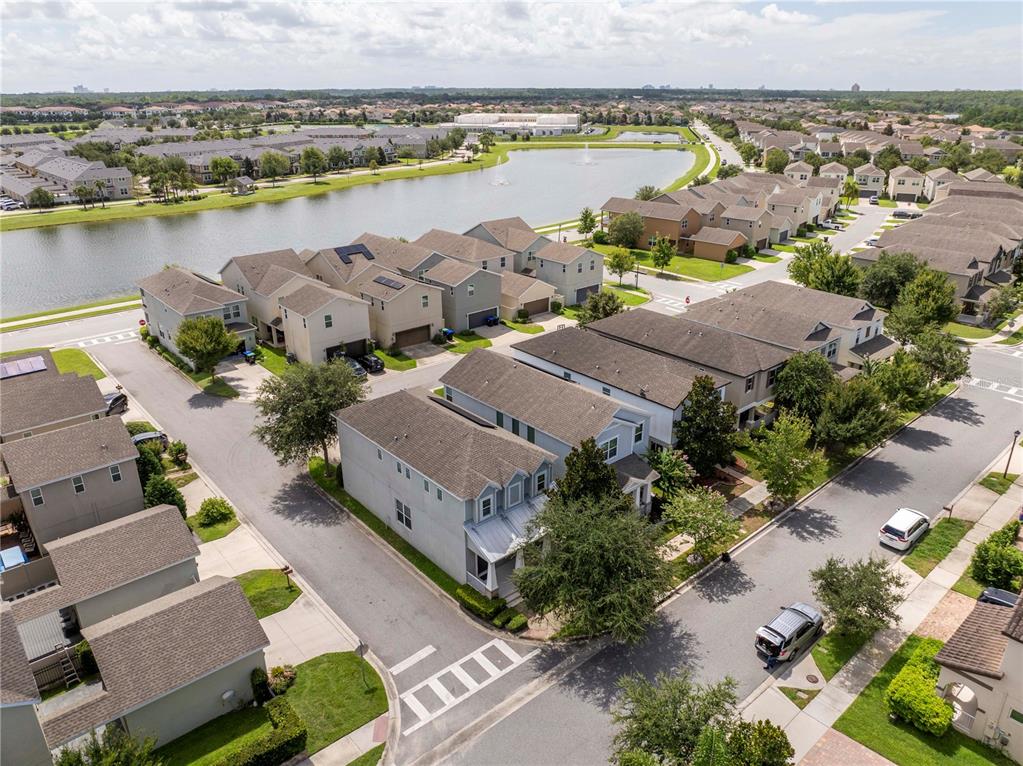 An aerial view shows a suburban neighborhood with townhouses, a pond, and paved streets — 8225 BRYCE CANYON AVENUE, WINDERMERE, FL