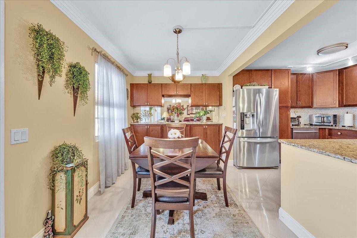 A dining area with a wooden table and chairs sits adjacent to a kitchen — 2047 Wolverton C # 2047, Boca Raton FL 33434, BOCA RATON, FL