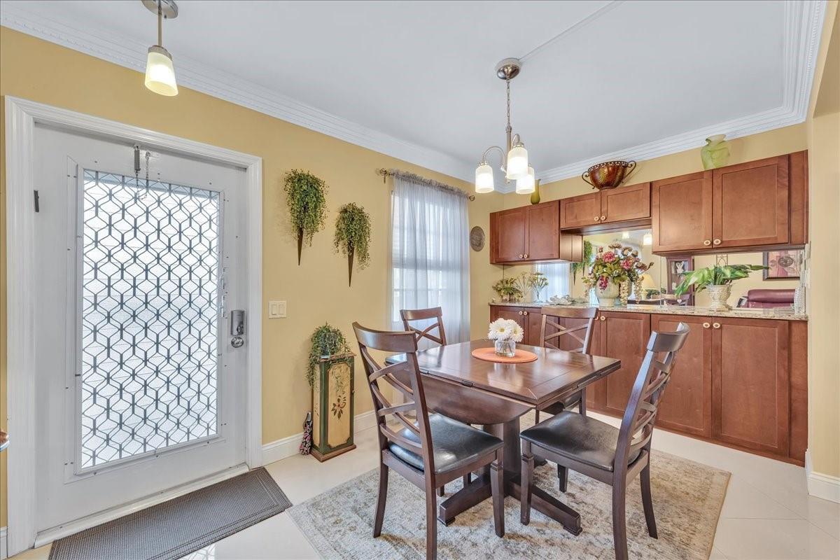 A dining area features a wooden table, four chairs, yellow walls, and brown cabinetry — 2047 Wolverton C # 2047, Boca Raton FL 33434, BOCA RATON, FL