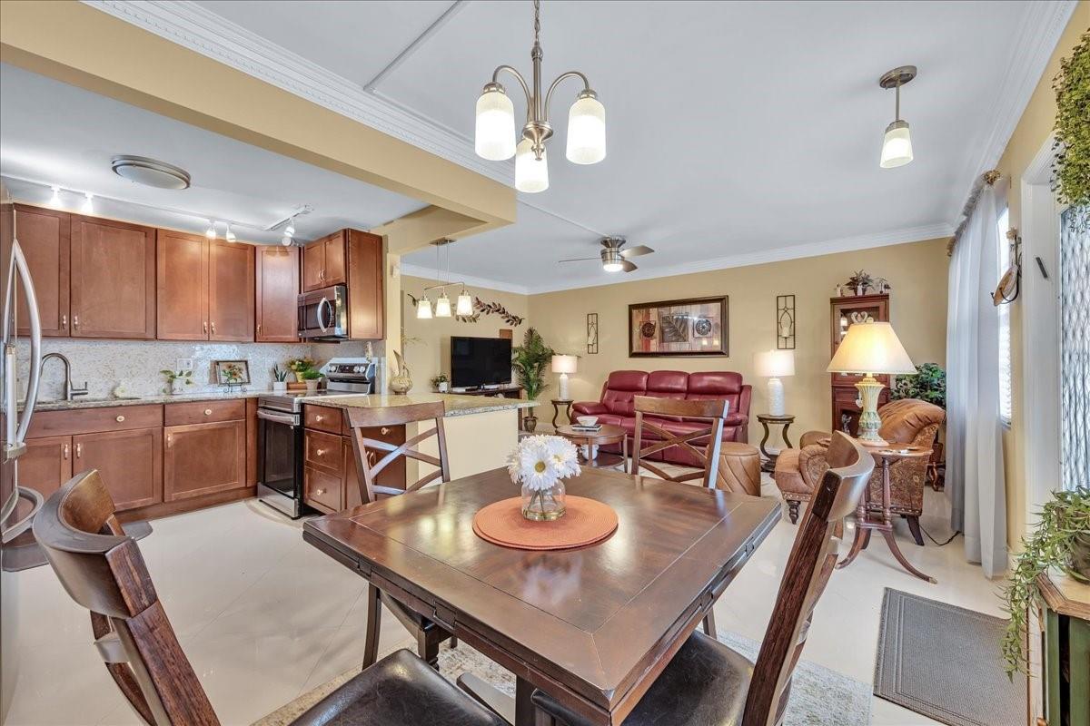 An open-concept kitchen, dining area, and living room with wood cabinets and tile flooring — 2047 Wolverton C # 2047, Boca Raton FL 33434, BOCA RATON, FL