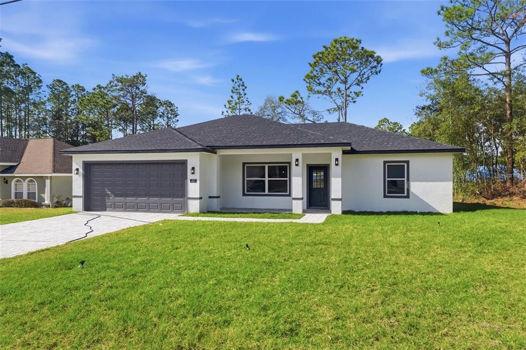 A single-story house with a gray garage door, white stucco exterior, and a dark roof — 2275 W LINDEN DRIVE, CITRUS SPRINGS, FL