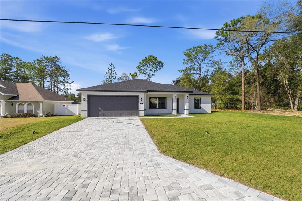 A single-story house with a gray garage door, white exterior, and a paved driveway — 2275 W LINDEN DRIVE, CITRUS SPRINGS, FL