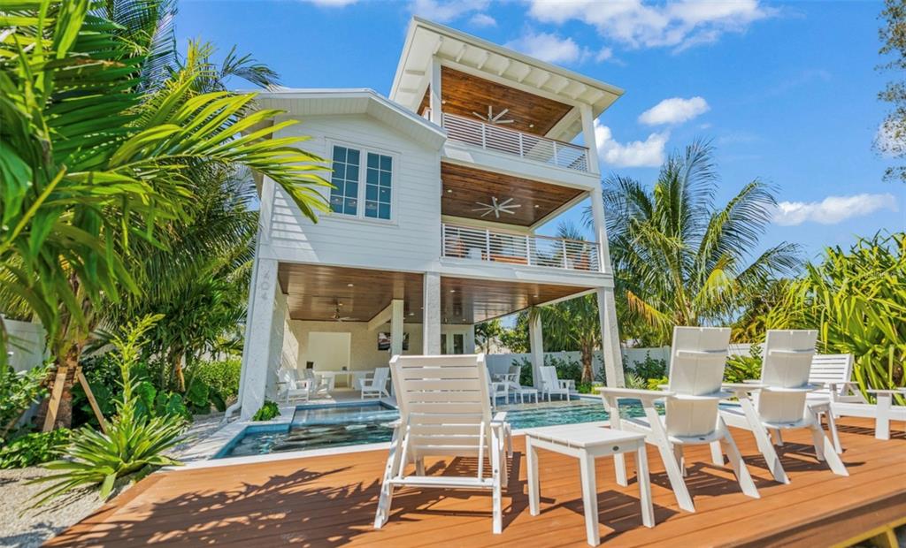 A three-story white house with balconies and a swimming pool on a wooden deck — 404 NORTH SHORE DR, ANNA MARIA, FL