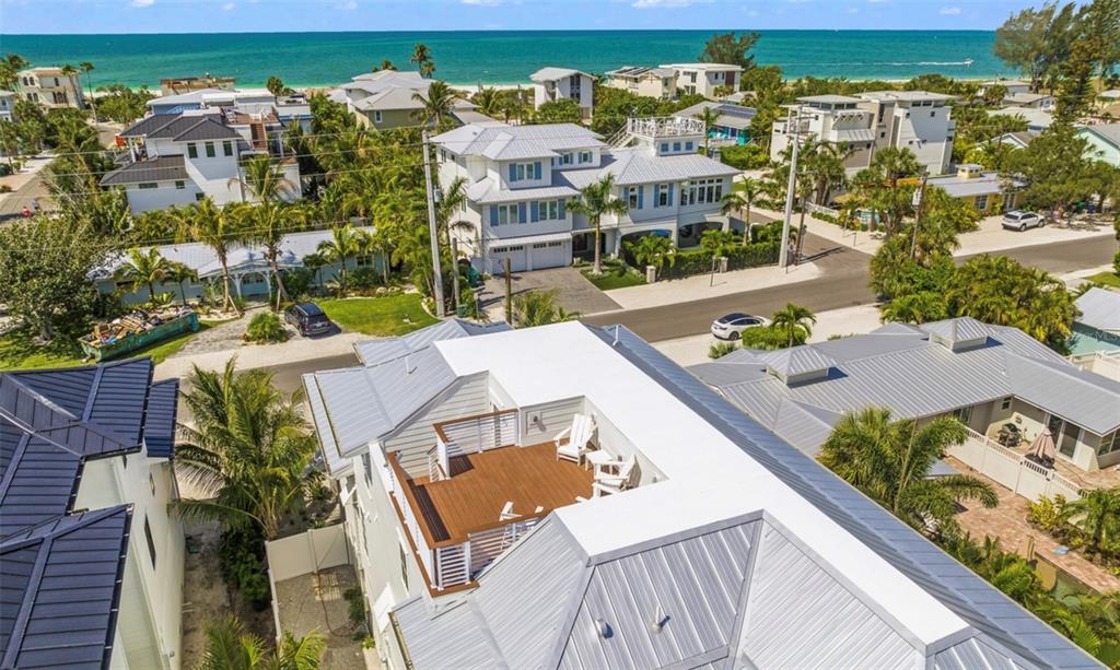An elevated aerial view shows a coastal house with a rooftop deck and metal roof — 404 NORTH SHORE DR, ANNA MARIA, FL