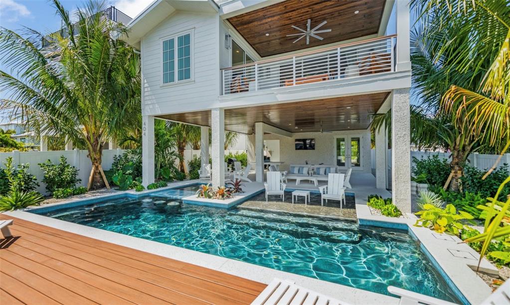 A two-story house with a swimming pool, covered patio, and wooden deck in the backyard — 404 NORTH SHORE DR, ANNA MARIA, FL