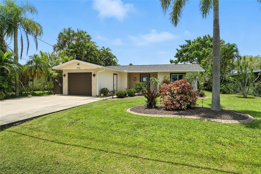 A single-story house with a brown garage door, light siding, and a landscaped front yard — 2131 SAINT CROIX AVENUE, FORT MYERS, FL