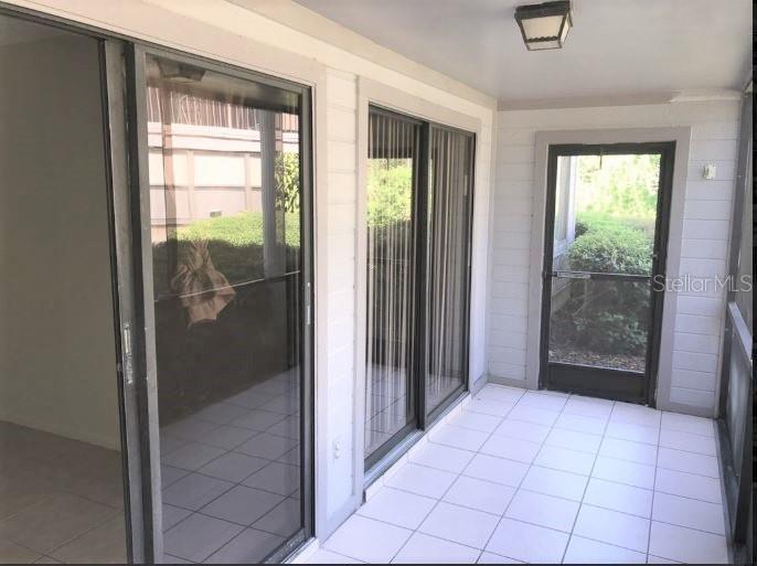 A tiled enclosed patio features sliding glass doors and a screen door leading outside — 2364 OAK PARK WAY UNIT 102, ORLANDO, FL