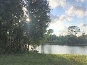 A grassy lawn leads to a lake surrounded by trees under a bright, cloudy sky — 2364 OAK PARK WAY UNIT 102, ORLANDO, FL