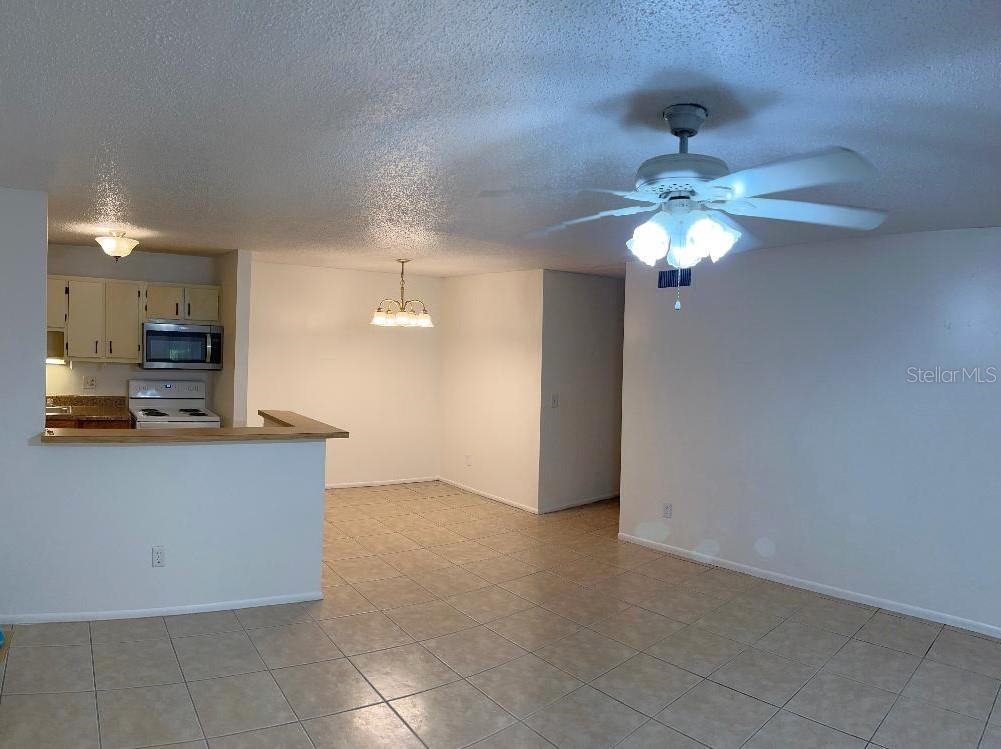 An open-concept living and dining area with tile flooring, a ceiling fan, and a kitchen — 2364 OAK PARK WAY UNIT 102, ORLANDO, FL