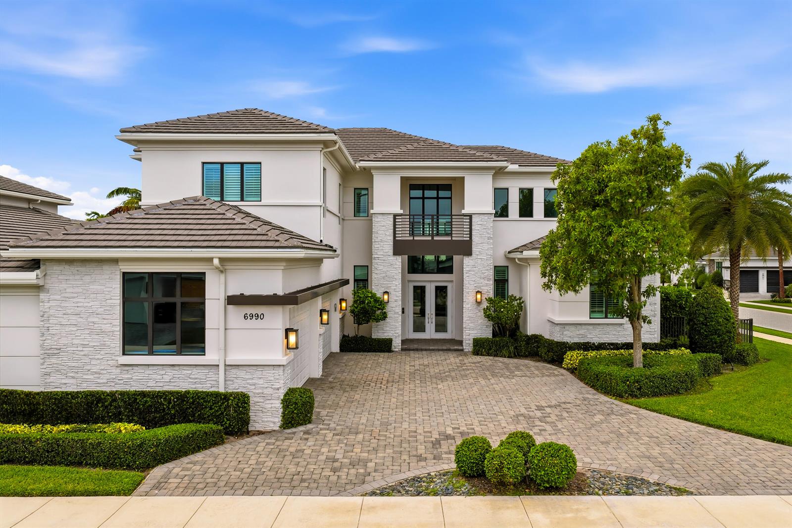 A two-story house with white stucco, stone veneer, a tiled roof, and a paved driveway — 6990 NW 27th Avenue, Boca Raton FL 33496, BOCA RATON, FL
