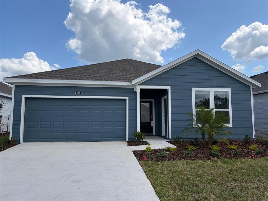A blue single-story house with a two-car garage, white trim, and a small front yard — 5548 MORANT BAY PATH UNIT B, KISSIMMEE, FL