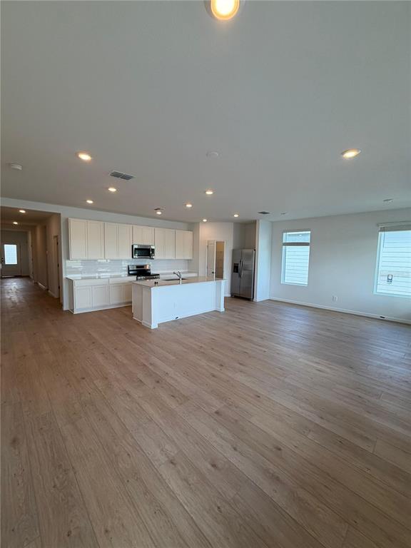 An open-concept kitchen features white cabinetry, a center island, and light wood-look flooring — 5548 MORANT BAY PATH UNIT B, KISSIMMEE, FL
