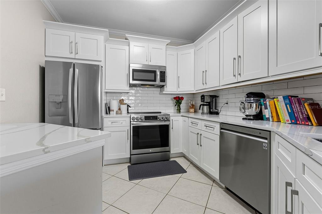 A kitchen with white cabinets, stainless steel appliances, a white countertop, and tiled flooring — 4333 BAYSIDE VILLAGE DRIVE UNIT 304, TAMPA, FL